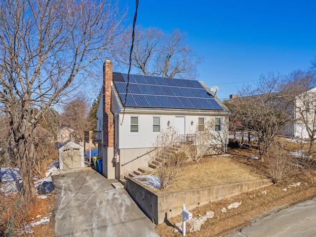 view of front of property with a chimney and solar panels