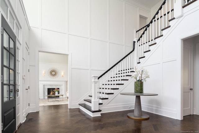 entryway featuring a towering ceiling, dark parquet flooring, and a premium fireplace