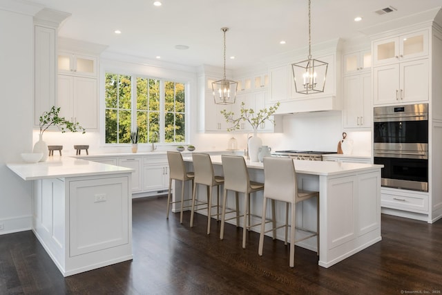 kitchen with a breakfast bar, hanging light fixtures, appliances with stainless steel finishes, a kitchen island, and white cabinets