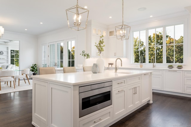 kitchen featuring stainless steel microwave, sink, decorative light fixtures, and an inviting chandelier