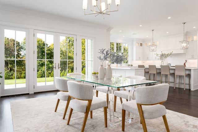 dining area featuring a wealth of natural light, dark wood-type flooring, ornamental molding, and a chandelier