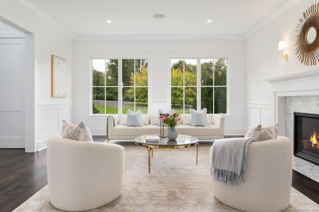 living room with crown molding, a premium fireplace, and a healthy amount of sunlight