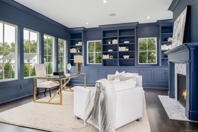 interior space with dark hardwood / wood-style flooring, built in shelves, a high end fireplace, and ornamental molding