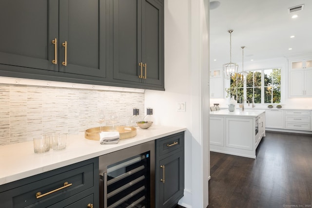 bar with wine cooler, dark wood-type flooring, white cabinets, pendant lighting, and backsplash