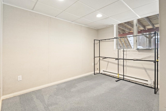 spare room featuring a drop ceiling, carpet, and a baseboard heating unit