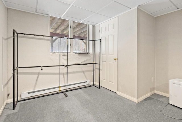 basement with a baseboard radiator, carpet flooring, and a paneled ceiling