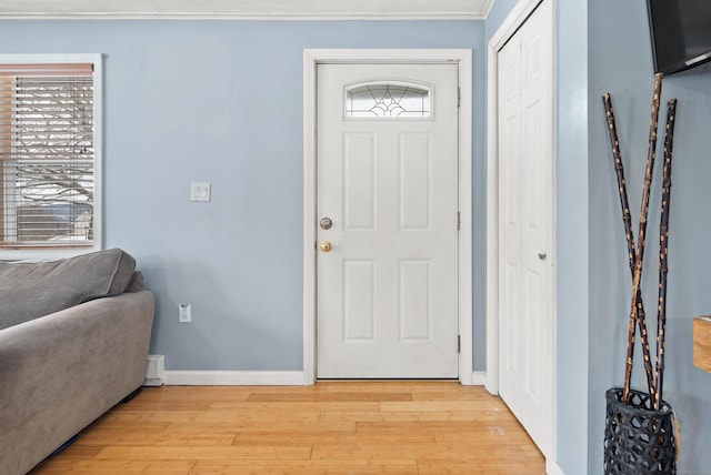 entrance foyer featuring ornamental molding, a healthy amount of sunlight, and light hardwood / wood-style flooring