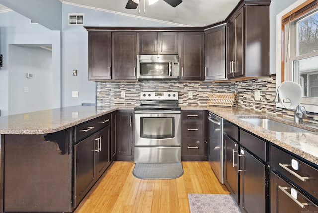 kitchen featuring tasteful backsplash, appliances with stainless steel finishes, vaulted ceiling, and light wood-type flooring