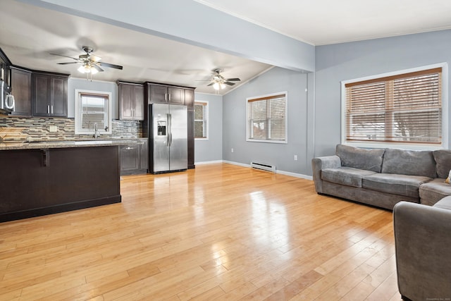 kitchen with appliances with stainless steel finishes, backsplash, vaulted ceiling with beams, dark brown cabinets, and light wood-type flooring