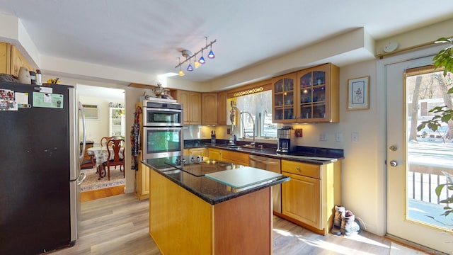 kitchen featuring appliances with stainless steel finishes, a center island, sink, and light hardwood / wood-style flooring