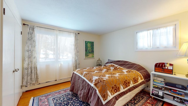 bedroom with a baseboard radiator and light hardwood / wood-style floors