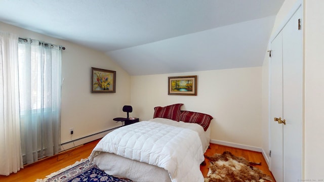 bedroom with vaulted ceiling, light hardwood / wood-style floors, and baseboard heating