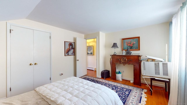 bedroom featuring lofted ceiling, hardwood / wood-style flooring, a closet, and baseboard heating