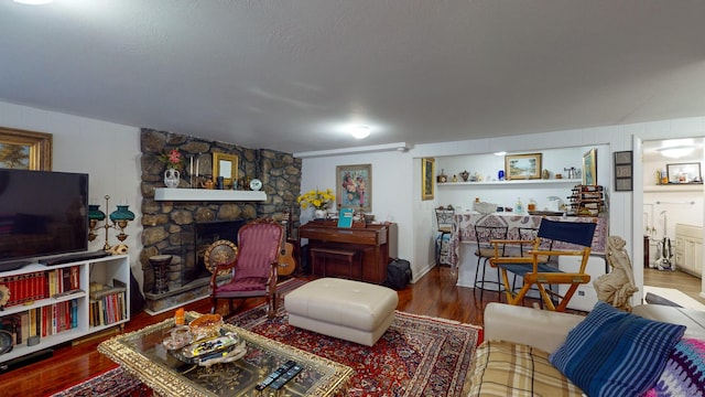 living room with hardwood / wood-style flooring and a stone fireplace