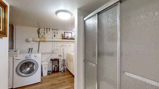 washroom featuring washing machine and dryer and light hardwood / wood-style flooring