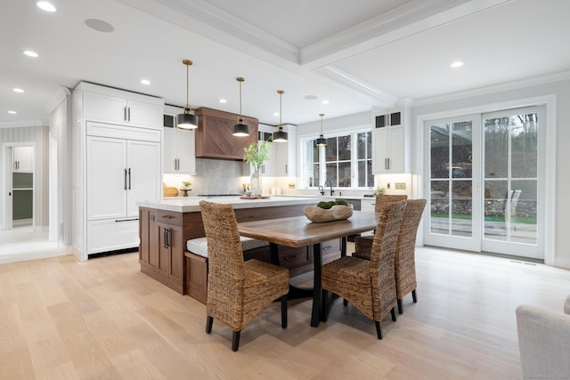 dining space featuring beamed ceiling, ornamental molding, and light wood-type flooring