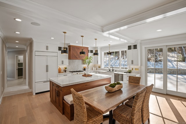 kitchen with pendant lighting, dishwasher, white cabinets, paneled built in refrigerator, and a center island