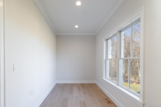 empty room with crown molding and light hardwood / wood-style floors