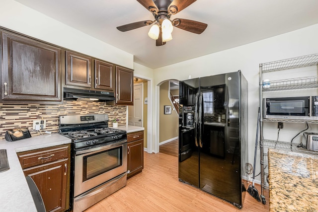 kitchen featuring tasteful backsplash, black refrigerator with ice dispenser, dark brown cabinets, stainless steel range with gas stovetop, and light hardwood / wood-style floors