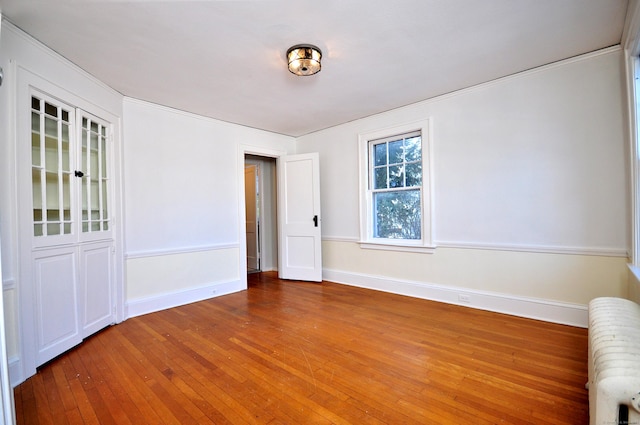 unfurnished room with hardwood / wood-style floors and radiator heating unit