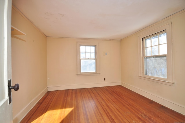 spare room featuring wood-type flooring, plenty of natural light, and crown molding