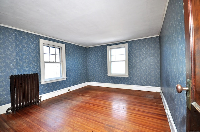 spare room featuring hardwood / wood-style flooring, radiator heating unit, and ornamental molding