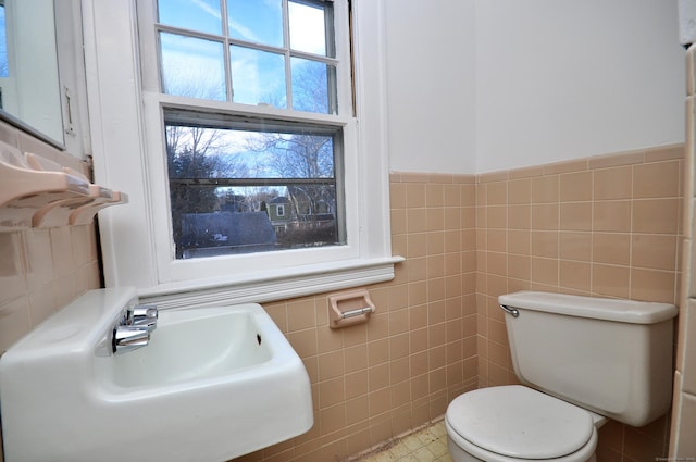 bathroom with sink, tile walls, and toilet