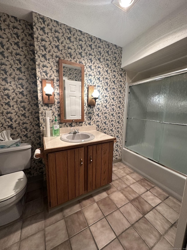 full bathroom featuring tile patterned floors, toilet, a textured ceiling, vanity, and enclosed tub / shower combo