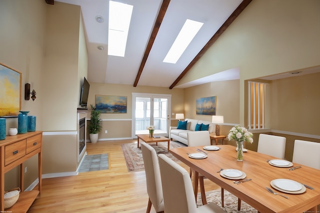 dining area featuring high vaulted ceiling, beam ceiling, a skylight, and light hardwood / wood-style floors