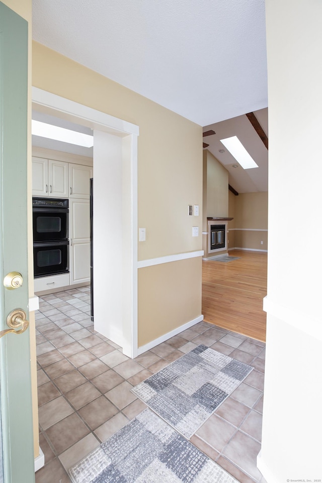 empty room with lofted ceiling with skylight and light tile patterned floors