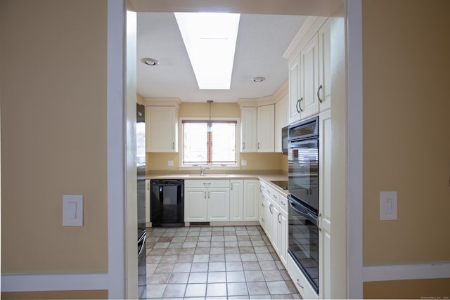 kitchen with light tile patterned flooring, sink, white cabinetry, a skylight, and black dishwasher