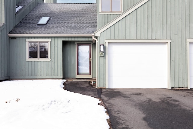 snow covered property entrance with a garage