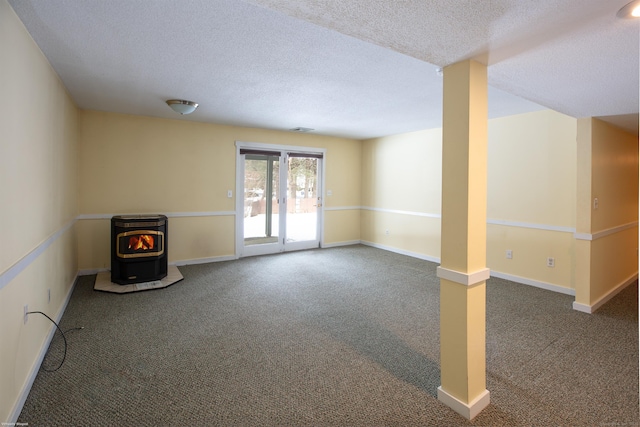 interior space featuring dark colored carpet, a textured ceiling, and a wood stove