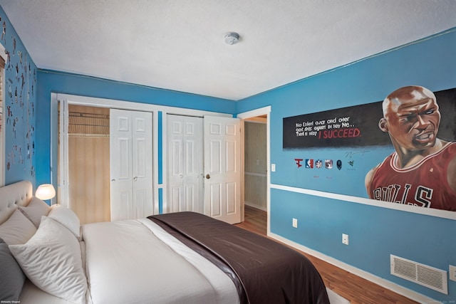 bedroom with hardwood / wood-style floors and two closets