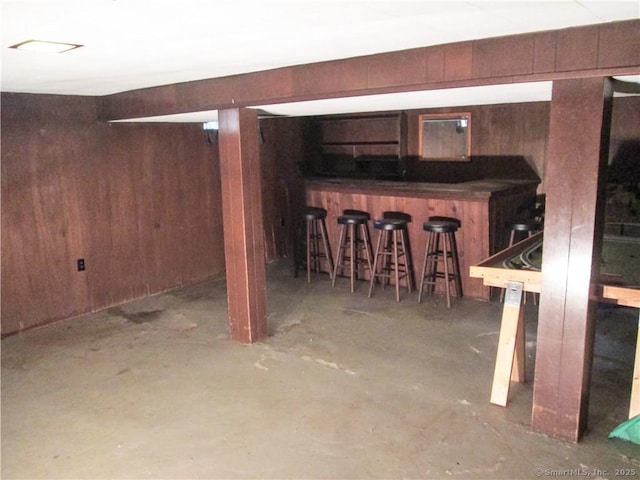 basement featuring indoor bar and wooden walls