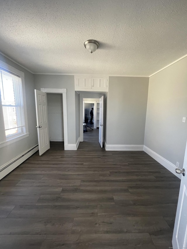 unfurnished bedroom featuring dark wood-type flooring, a closet, a textured ceiling, and baseboard heating