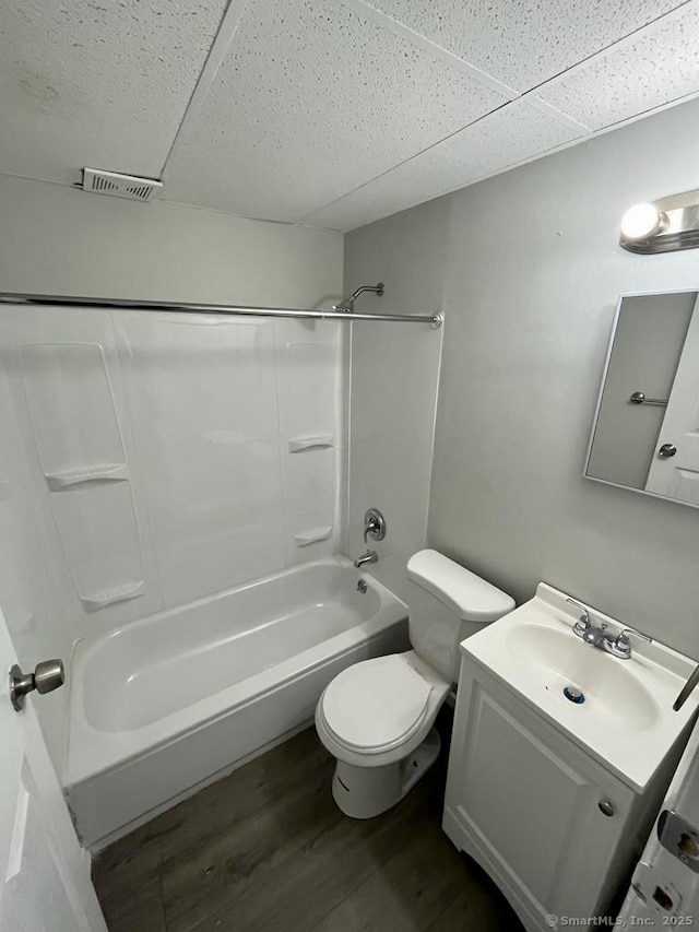 full bathroom with a paneled ceiling, hardwood / wood-style floors, vanity, bathtub / shower combination, and toilet