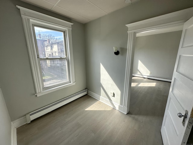 interior space featuring a baseboard radiator, hardwood / wood-style floors, and a drop ceiling