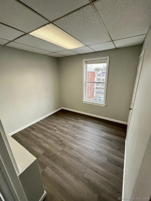 basement featuring dark wood-type flooring and a drop ceiling