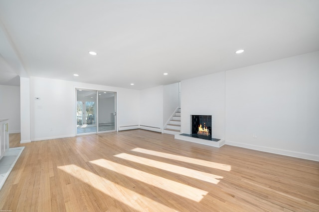 unfurnished living room featuring light hardwood / wood-style flooring and a baseboard heating unit