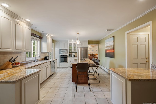 kitchen featuring appliances with stainless steel finishes, decorative light fixtures, sink, decorative backsplash, and a center island