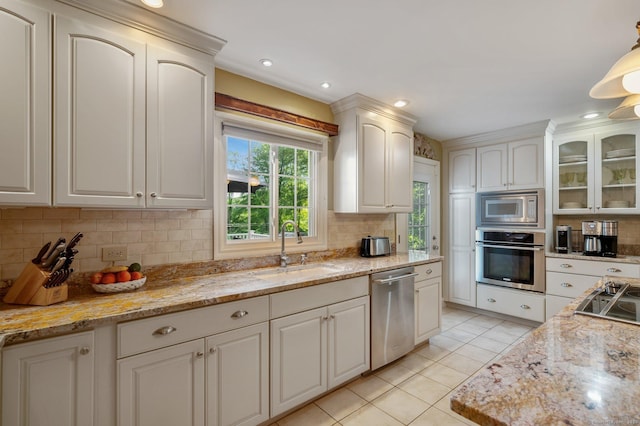 kitchen with decorative light fixtures, sink, white cabinets, decorative backsplash, and stainless steel appliances