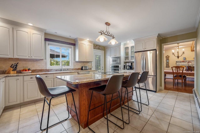 kitchen with a kitchen island, appliances with stainless steel finishes, white cabinets, and decorative light fixtures