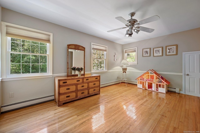 rec room with wood-type flooring, plenty of natural light, and baseboard heating