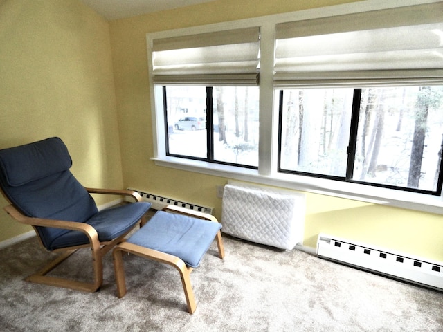 sitting room featuring a baseboard heating unit, a wealth of natural light, and light colored carpet