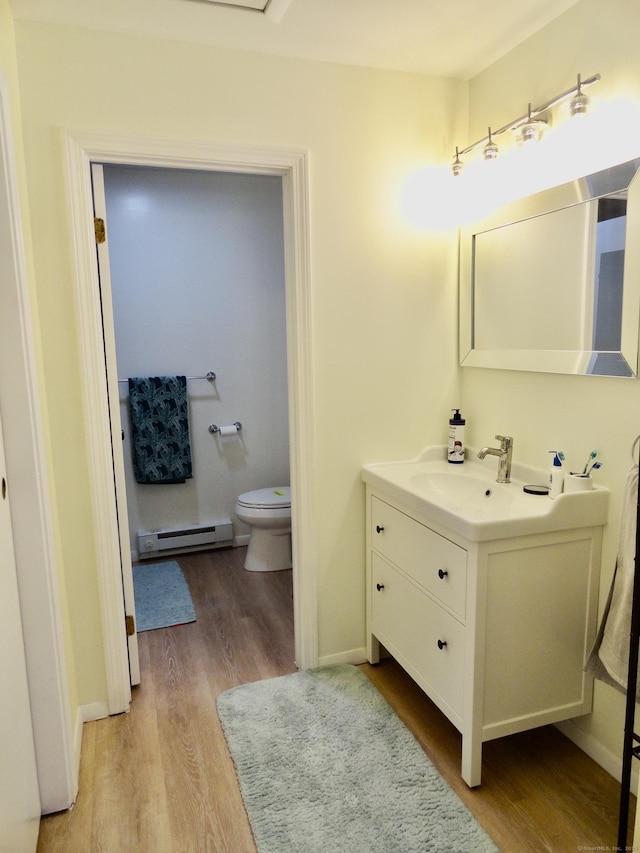 bathroom featuring vanity, toilet, hardwood / wood-style floors, and a baseboard heating unit