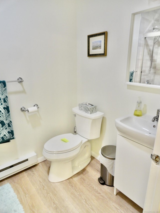 bathroom featuring hardwood / wood-style flooring, vanity, baseboard heating, and toilet