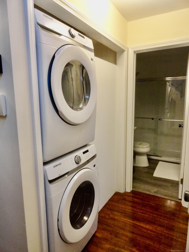 laundry area featuring stacked washer / drying machine and dark hardwood / wood-style floors