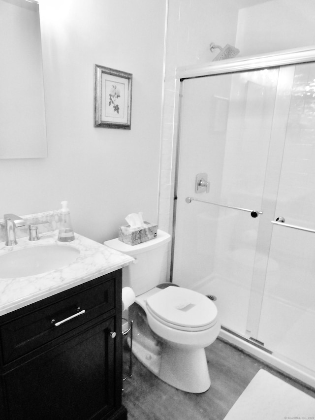 bathroom with vanity, hardwood / wood-style floors, a shower with door, and toilet