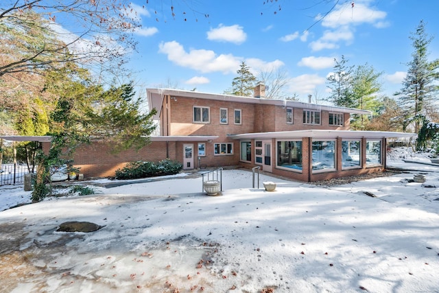 snow covered property featuring a sunroom